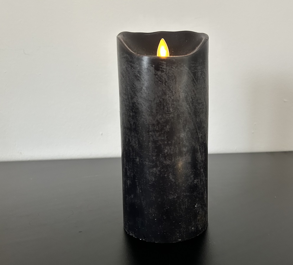 eine schwarze brennende kerze als symbol für abschied und trauer